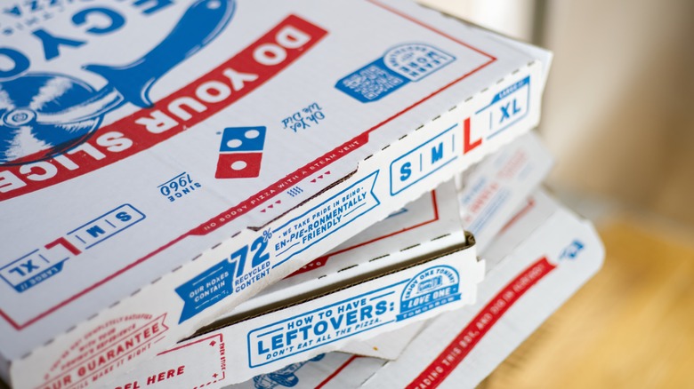Domino's pizza boxes sit in a stack.