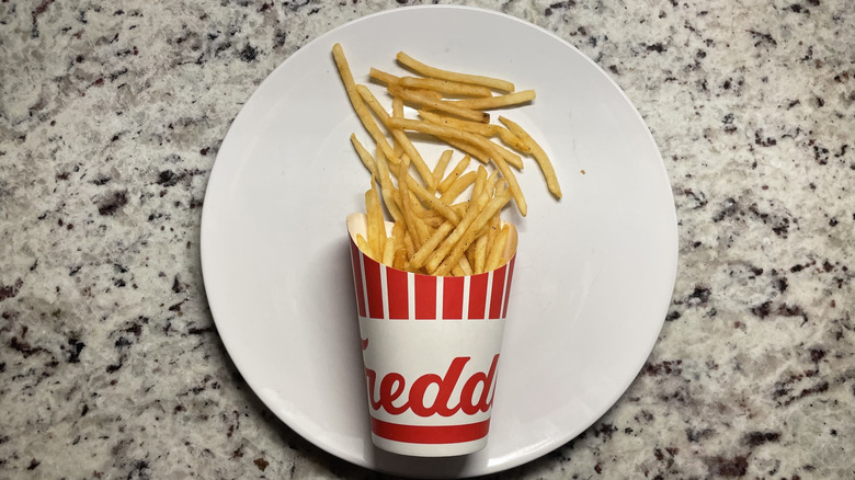 Freddy's French fries in a container and on a plate