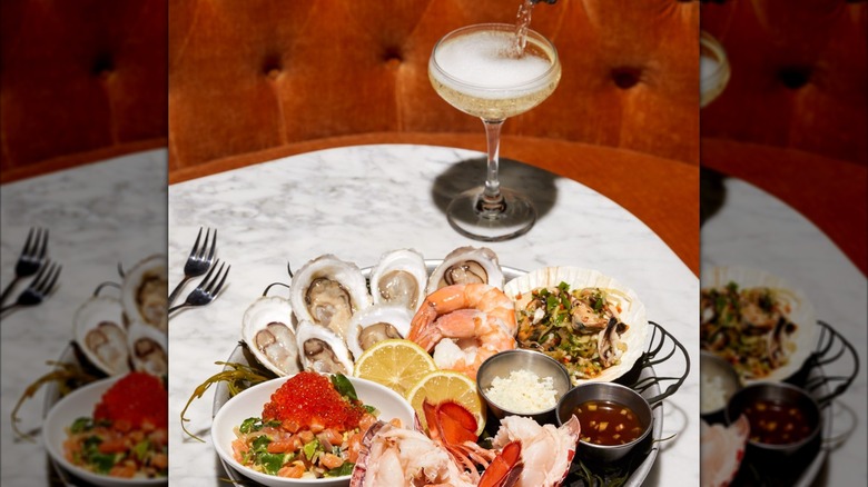 Seafood platter with oysters and shrimp on table with champagne cocktail
