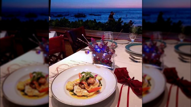 Dish of steamed fish on table with view overlooking the ocean