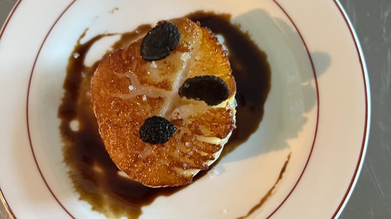Scallop and truffle with glaze on white plate