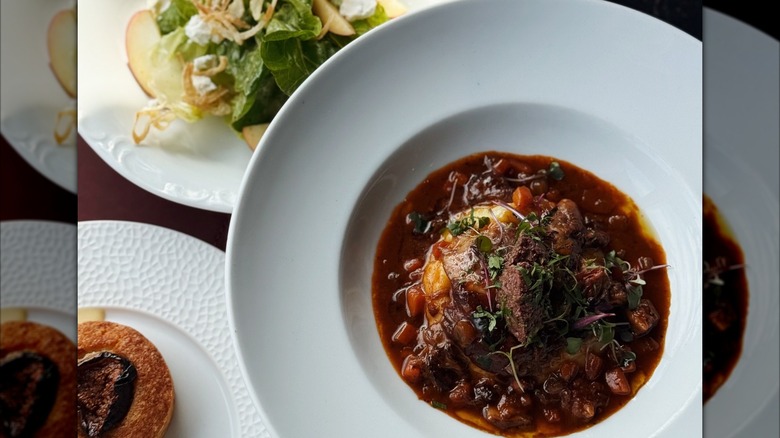 Brasied lamb in sauce with salad in background