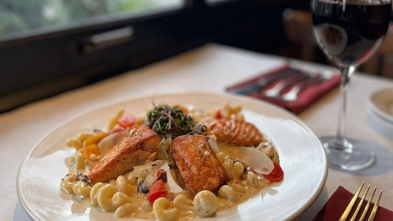 Mediterranean pasta with salmon and wine glass in background