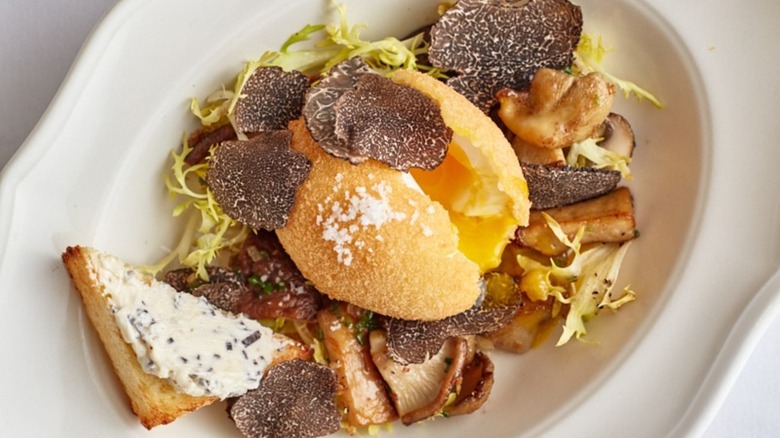 Dish with shaved truffles, mushrooms, and greens
