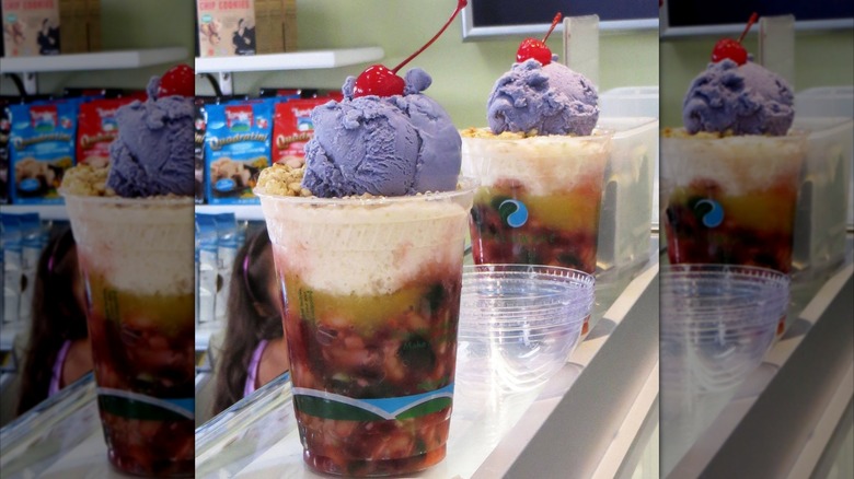 Two plastic cups of halo halo sundaes with ube ice cream and cherries on top