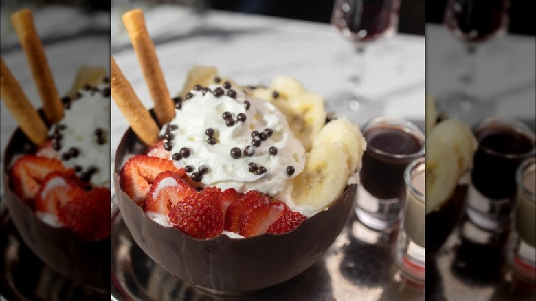 Ice cream sundae in a chocolate bowl with shots of liqueur on the side
