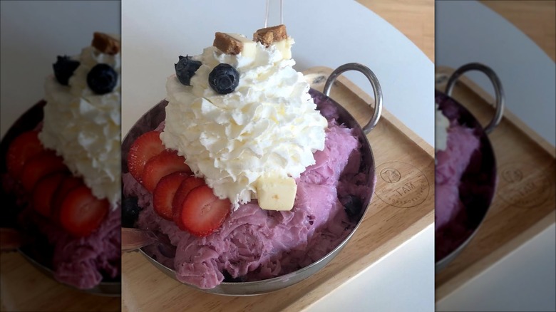 Shaved ice cream in a bowl, topped with fruit and whipped cream