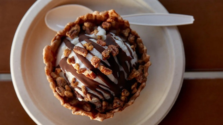 Overhead shot of ice cream in a waffle bowl with chocolate and candied pecans on top