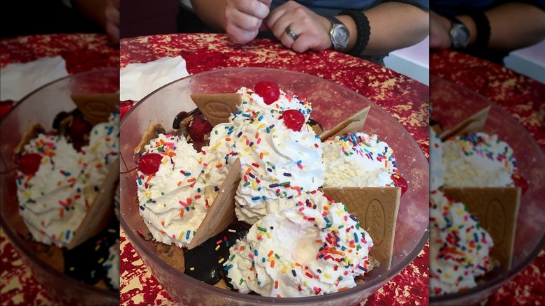 Tchoupitoulas sundae in a glass bowl, topped with whipped cream, sprinkles, and cherries