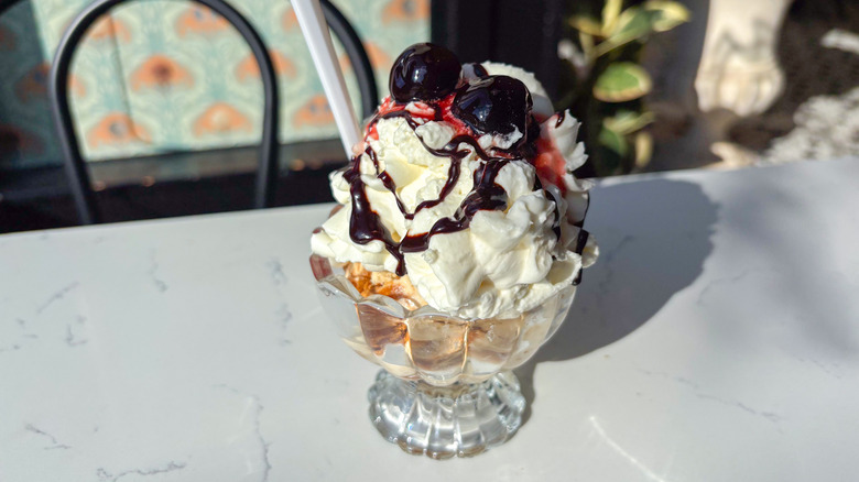 Ice cream sundae in glass bowl with whipped cream and two cherries on top