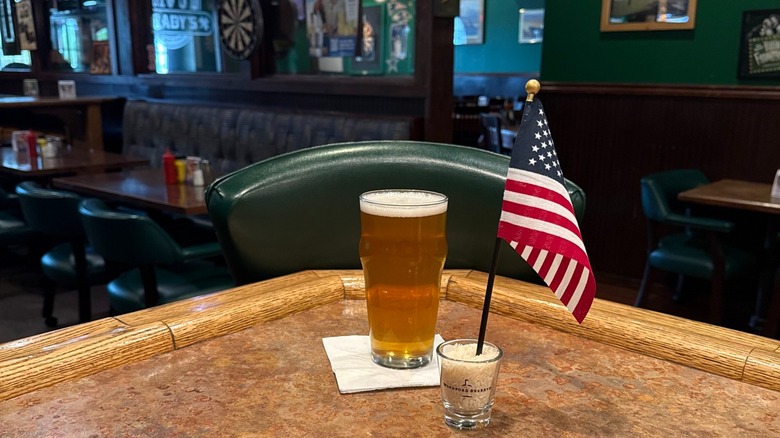 Pint of beer and American flag on corner of bar with empty pub in background
