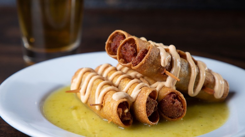 Corned beef taquitos on plate with sauce