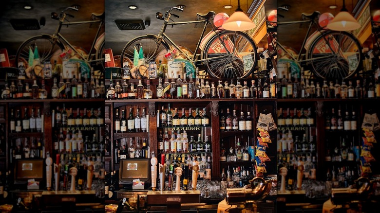 Wall of bottles behind the bar with bicycle on top