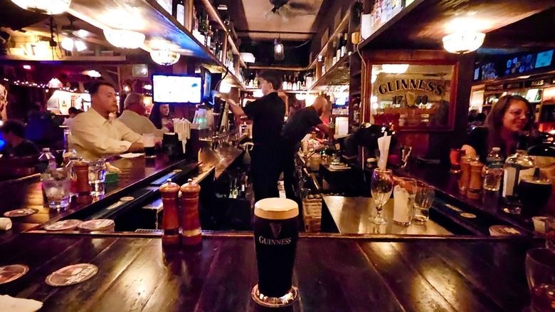 Busy pub with customers at bar and pint of Guinness in center
