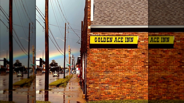 Exterior of brick building with Golden Ace Inn sign and rainbow in background