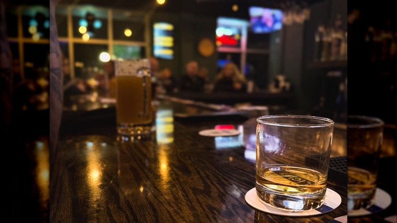 Glass of whiskey on table with pub interior blurred background