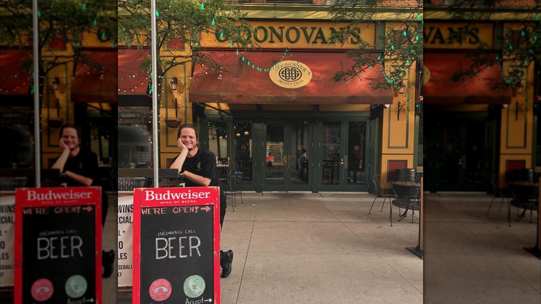 Exterior of O'Donovan's pub with man leaning on advertising sidewalk sign