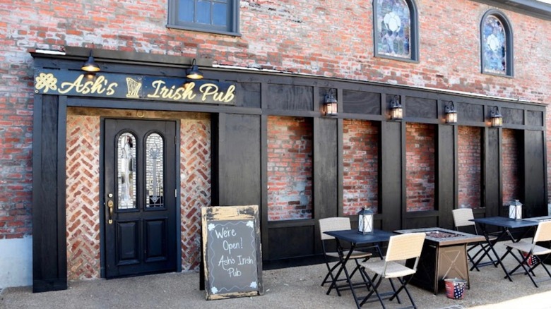 Exterior of Ash's Irish Pub brick building with tables and chairs outside