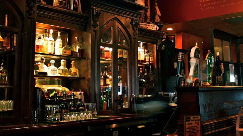 Dimly lit bar with taps and brightly lit liquor cabinets