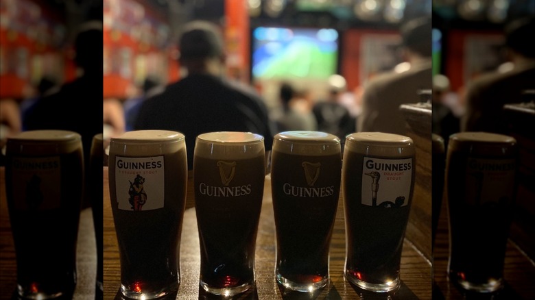 Pints of Guinness on bar with customers blurred in background