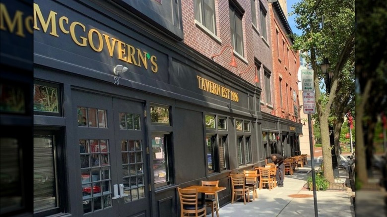 Exterior of McGovern's black and brick front building with tables and chairs