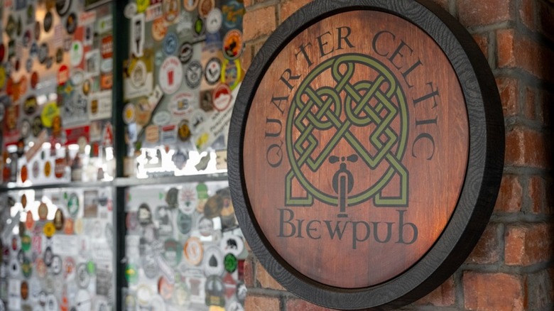 Quarter Celtic sign on brick wall by sticker-covered window