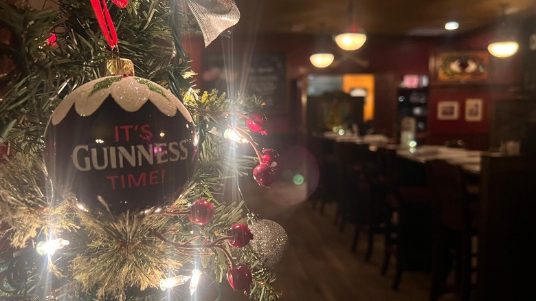 Guinness ornament on tree with pub tables and chairs blurred background