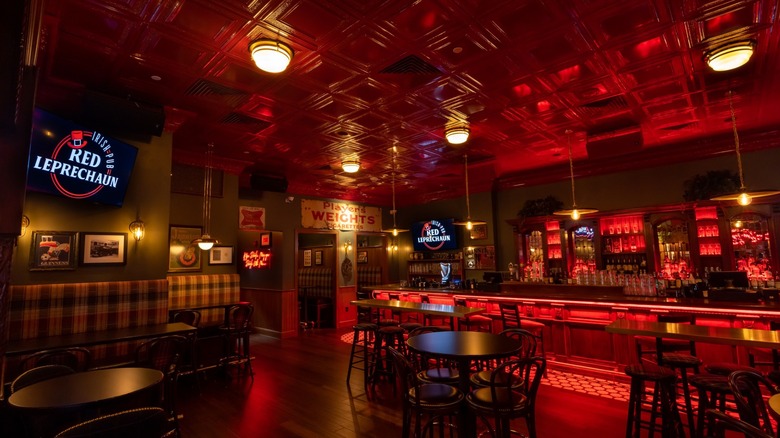 Bar with tables and chairs, Red Leprechaun signs, and red lighting