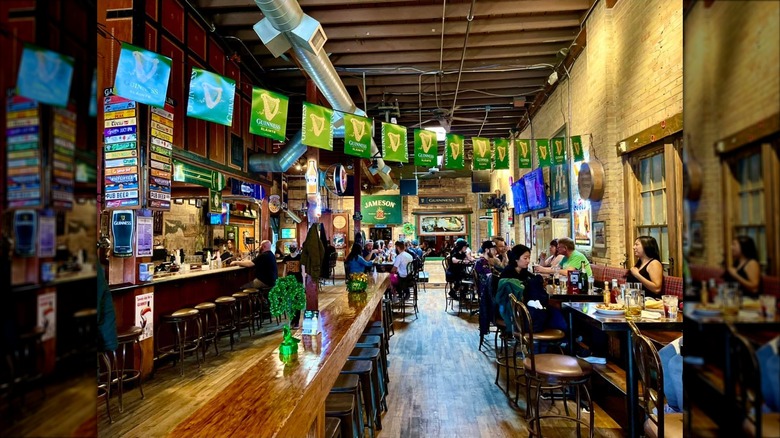 Interior of pub with tables and chairs, a middle bar, and left bar, with wood and yellow brick
