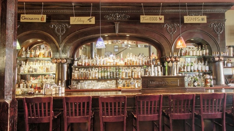 Bar with mirrored back bar, bottles, and signs for growlers, eggs, and stamps