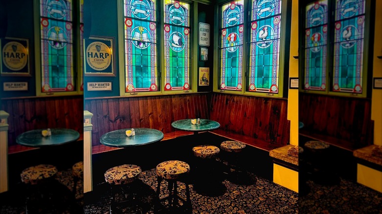 Corner sitting area with benches, tables, stools, and stained glass windows