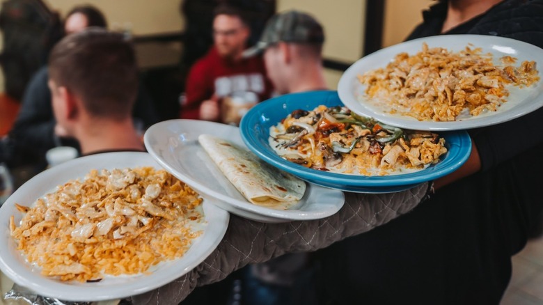 Four plates of assorted Mexican dishes carried on an arm