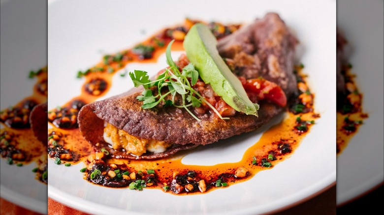 Blue corn tortilla on a plate with chili drizzle