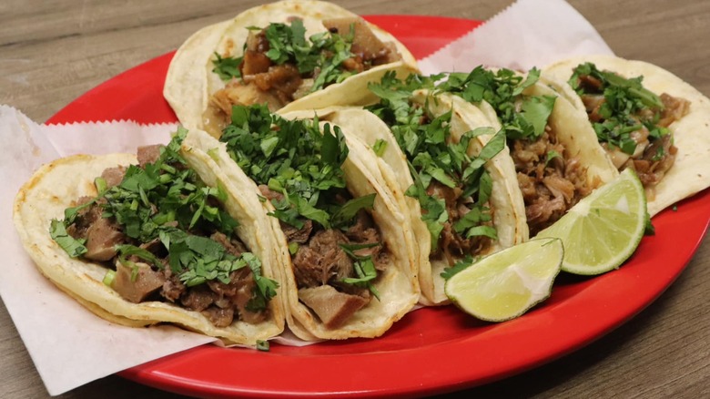 Plate of six tacos with wedges of lime