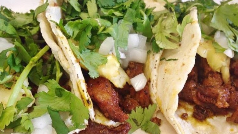 Close-up on three tacos with onion and cilantro