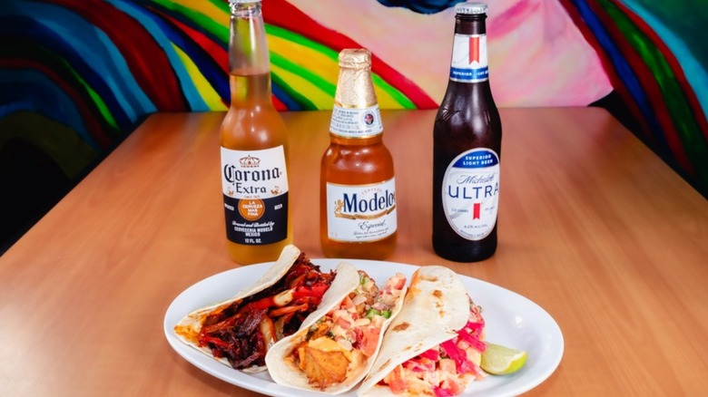 Plate of three assorted tacos with three bottles of beer