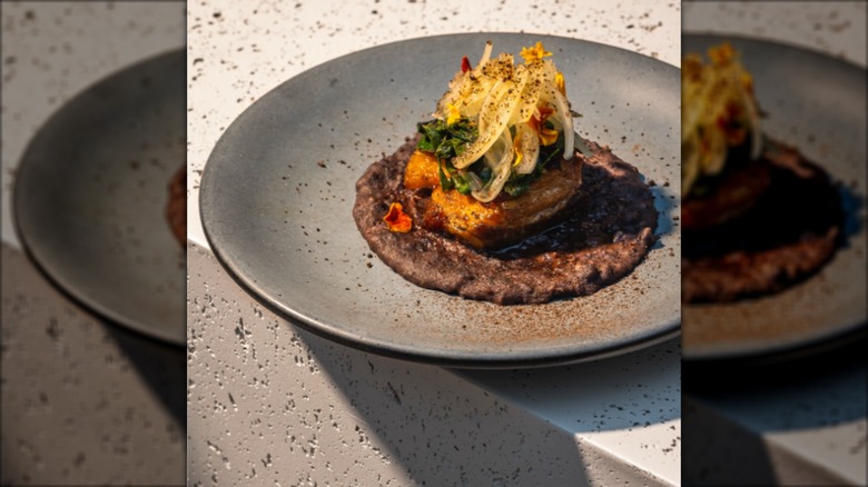 Pork belly, onions, and swiss chard dish on grey plate