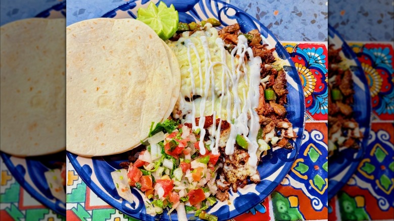 Plate of deconstructed tacos with pico, crema, lime, and tortillas
