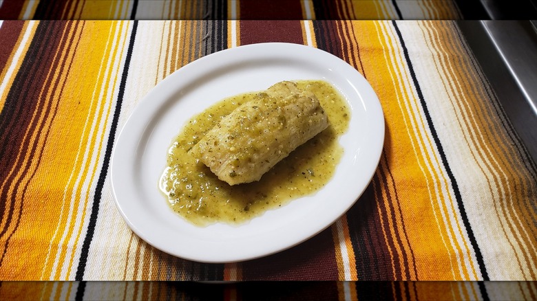 Tamale with green chile sauce on colorful background