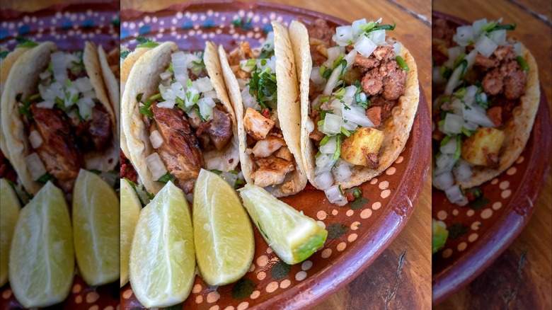 Tacos on brown plate with slices of lime