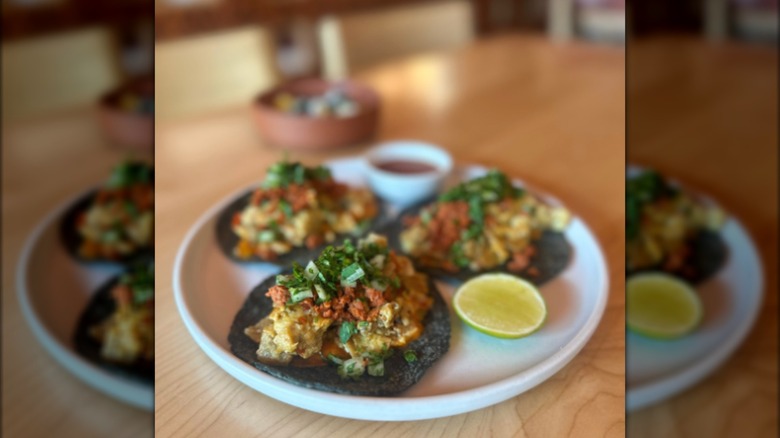 Three blue corn torilla breakfast tacos on plate with lime