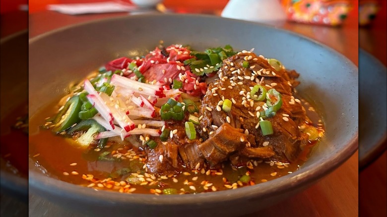 Birria ramen in bowl with shredded veg