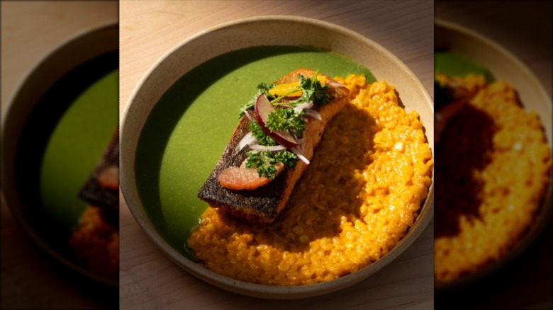 Grilled salmon in dish on top of soup and rice