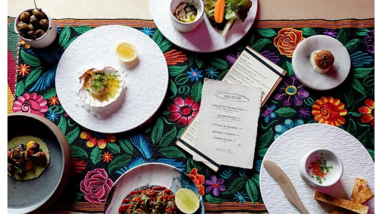 Assortment of bar bites Mexican dishes on colorful floral background