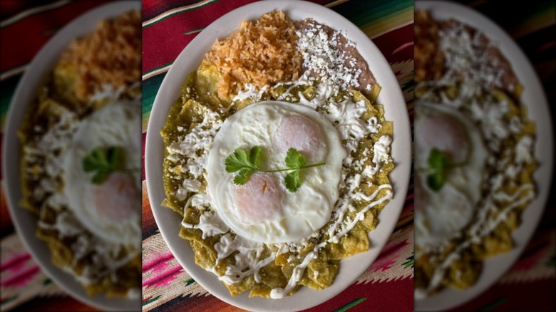 Chilsaquiles with rice and beans on white plate and colorful background