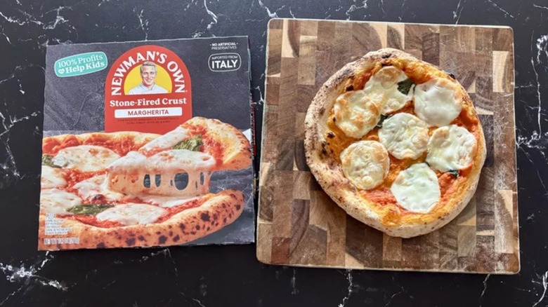 Newman's Own Margherita frozen pizza on a cutting board and marble surface
