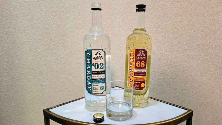 A bottle of Charbay Clear Vodka and Meyer Lemon Vodka on a table with a rocks glass