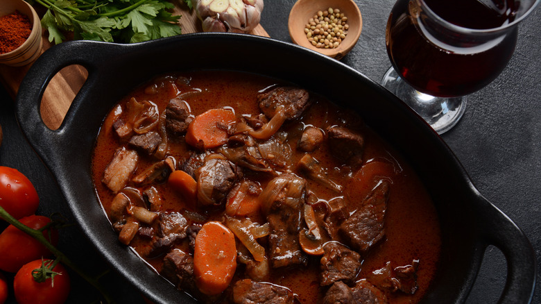 Beef stew in pot with glass of red wine