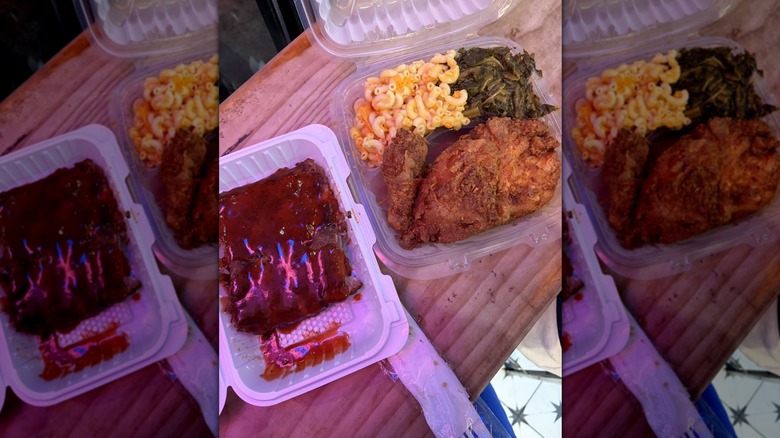 BBQ ribs, fried chicken, mac and cheese, and collard greens in takeout containers.