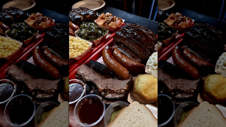 A variety of smoked meats, including brisket and sausage, on a tray with sauces and sides.